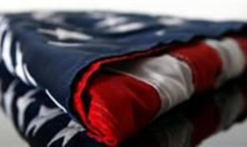 A folded American flag with visible stars and stripes, placed on a reflective surface.